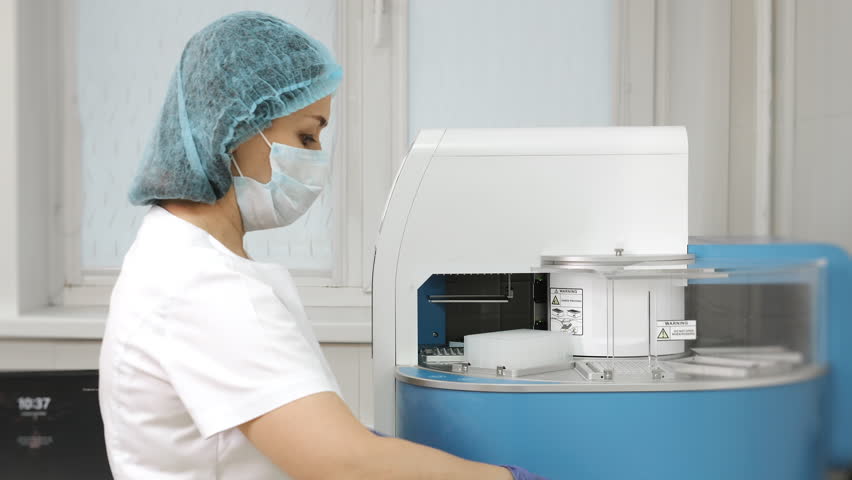 Medical laboratory technician operating automated nucleic acid extraction station for PCR testing in modern clinical lab environment.