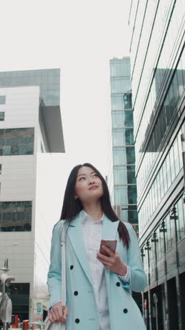 successful asian woman walking city street talking phone vertical video symbol financial independence business success leadership modern lifestyle confident professional money mindset