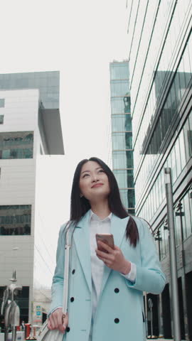 successful asian woman walking city street talking phone vertical video symbol financial independence business success leadership modern lifestyle confident professional money mindset
