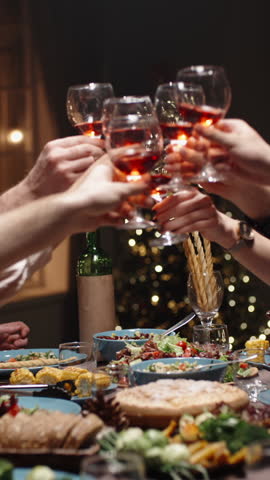 Vertical slow motion video cinematic camera moving above festive dinner table red wine glasses meeting in toast concept celebration togetherness thanksgiving christmas cozy home light