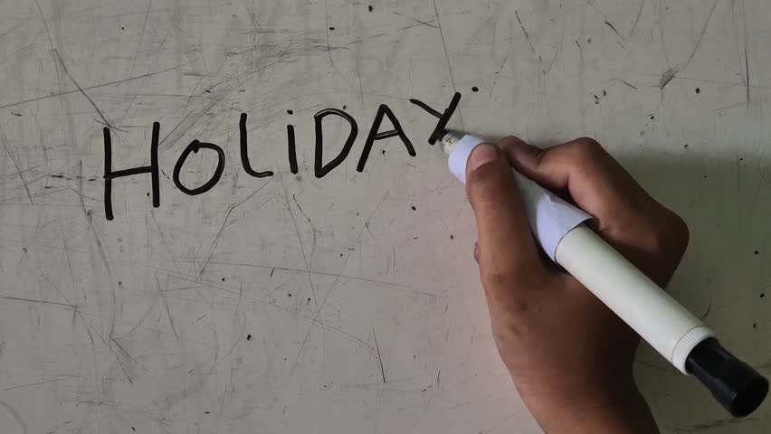 The hands of elementary school boy write the word holiday on the whiteboard. fast motion