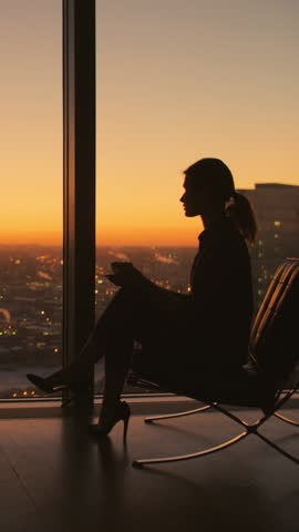 silhouette of businesswoman drinking coffee by window city sunset vertical video modern lifestyle success balance independence motivation urban professional elegance confidence