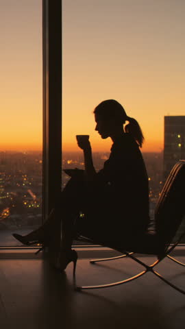 silhouette of businesswoman drinking coffee by window city sunset vertical video modern lifestyle success balance independence motivation urban professional elegance confidence