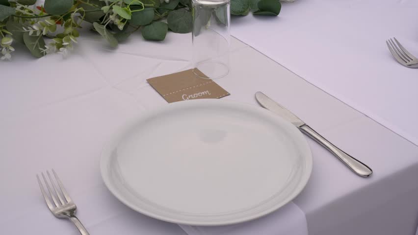 A beautifully arranged table awaits guests, featuring white tableware, elegant cutlery, and floral accents. The setting is perfect for a memorable celebration or gathering.