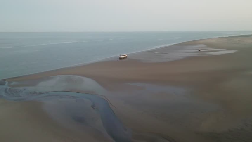 Head-on wide view at daybreak of a boat grounded on the tidal flat with mirrorlike water and layered sandbanks. Wadden Sea.