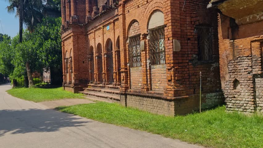 Abandoned colonial mansion in Panam Nagar, Sonargaon, Bangladesh, surrounded by palm trees and tropical vegetation on a sunny day, showcasing historic architecture and overgrown surroundings
