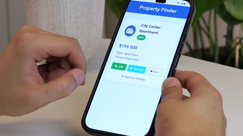 Close up of a mans hands using a smartphone to browse real estate listings. He carefully reads an ad for a central city apartment, saves it to his favorites, and continues his search.