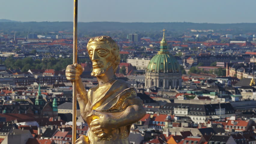 Aerial drone view of the golden statue atop a sphere on the Church of Our Saviour overlooking the Copenhagen skyline, with Frederik