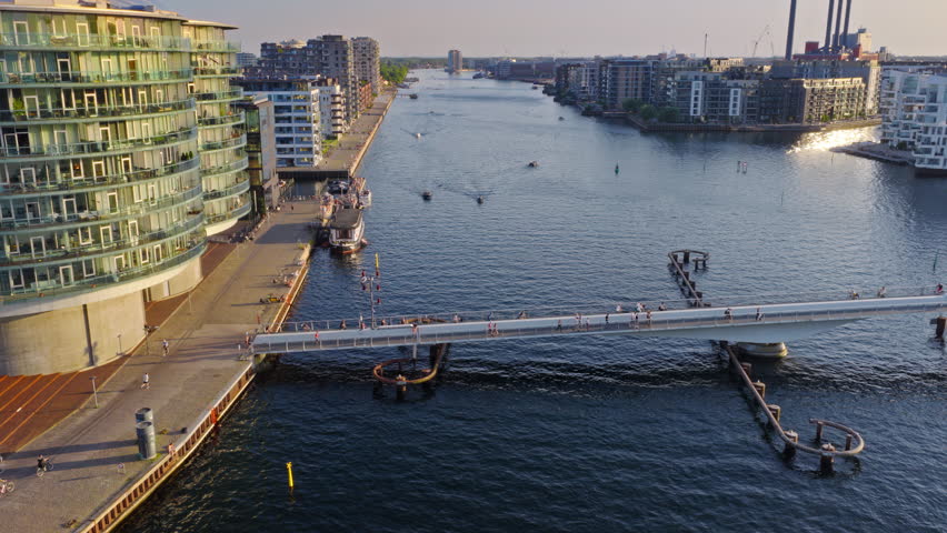 Aerial drone view of the Lille Langebro pedestrian bridge with people cycling and walking across the harbour at sunset in Copenhagen, Denmark