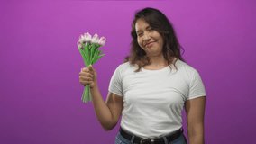 Young woman smiling holding pink tulips with hand visible in magenta studio; joy celebration warmth spring. - Powered by Shutterstock - Get 15% off with code: PIKWIZARD15