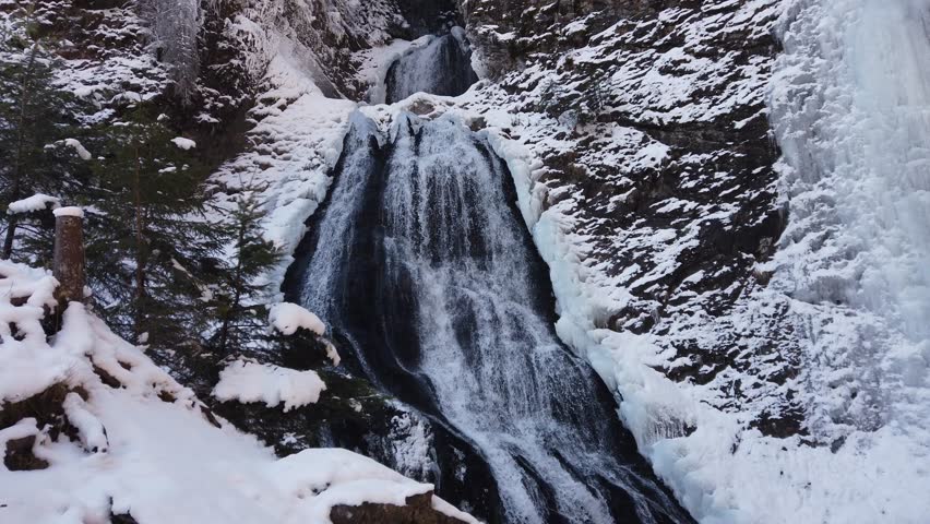 Waterfall in the mountains during extreme cold winter with icicles. Rachitele, Romania