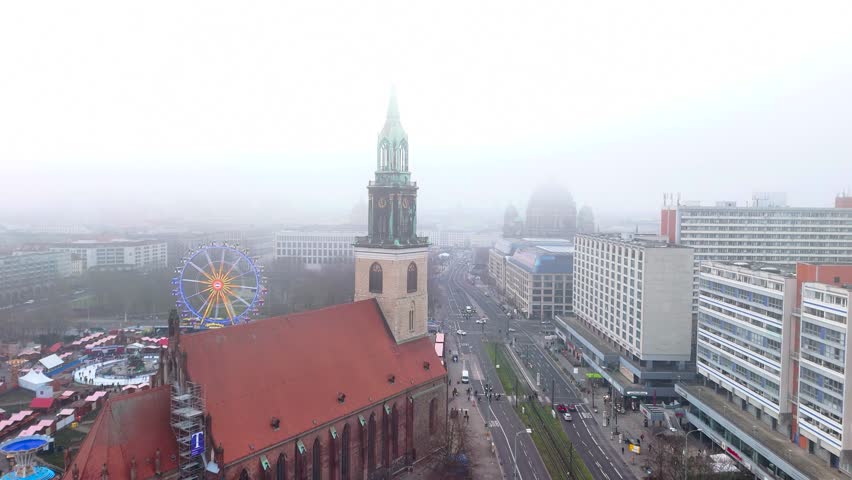 A stunning aerial view showcases a historic tower amidst a foggy city landscape. A colorful fairground with a Ferris wheel brightens the scene, adding festive cheer.