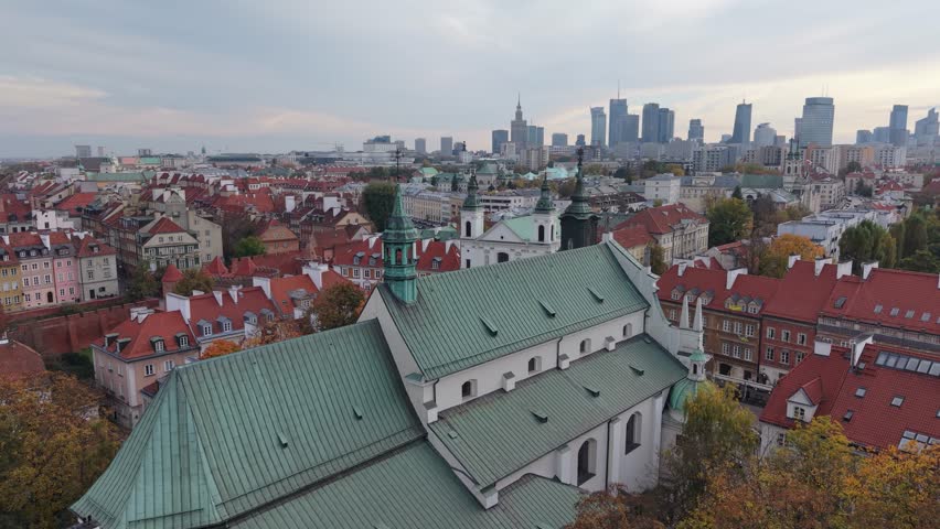 Aerial drone flyby near the historic Dominican Order Church in Warsaw’s Old Town, Poland, showing its elegant architecture surrounded by narrow streets and colorful rooftops.