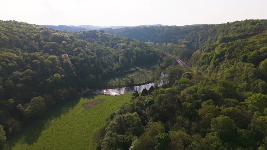 thick jungle railway line below surrounded by green cover covered mountains aerial flying shot forest dense vegetation train tracks natural landscape remote area