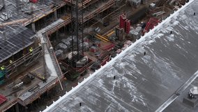 High-angle drone image showing a large-scale construction site with workers, scaffolding, rebar, formwork, and materials during the concrete framework phase of a multi-story building. - Powered by Shutterstock - Get 15% off with code: PIKWIZARD15