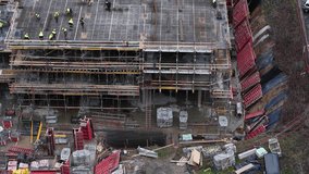 High-angle drone image showing a large-scale construction site with workers, scaffolding, rebar, formwork, and materials during the concrete framework phase of a multi-story building. - Powered by Shutterstock - Get 15% off with code: PIKWIZARD15