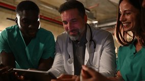 Diverse group of doctors and nurses having a meeting late at night in a hospital office, discussing a case using a digital tablet - Powered by Shutterstock - Get 15% off with code: PIKWIZARD15