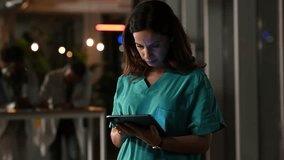 Medical assistant in green scrubs working overtime, typing on a digital tablet. The dedicated professional is concentrating on patient data - Powered by Shutterstock - Get 15% off with code: PIKWIZARD15