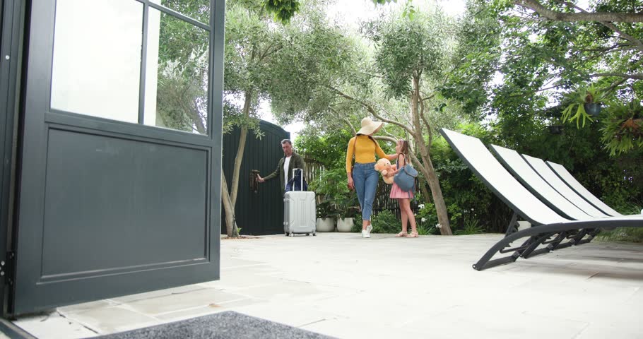 Diverse family unlocking gate, entering dining room, placing suitcases and hats, sharing hug. Family, reunion, outdoor, lifestyle, candid, candidshot, home
