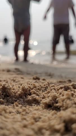 Two young children are playing with sand on the beach