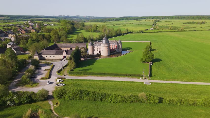 castle lavaux sainte anne or château de full compound green cover water body fields corner cars trees hills town to left around right pans drone panning