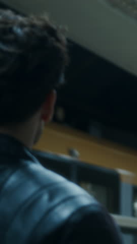 Man in leather jacket stands on underground platform watching a moving subway train, capturing urban travel and cinematic night mood. vertical video