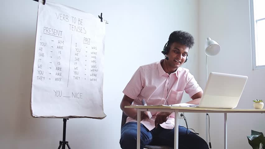 Engaged young teacher leading online English lesson on verb conjugations for remote students