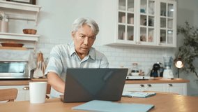 Stressed manager with casual cloth sitting at table while looking at financial chart from laptop. Unhappy senior businessman check financial report with deceasing sales. Unhealthy concept. Myrmidon. - Powered by Shutterstock - Get 15% off with code: PIKWIZARD15