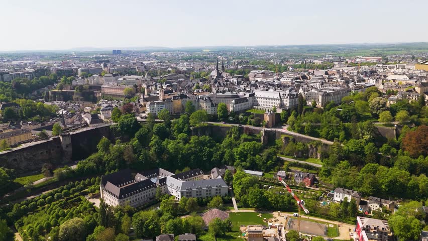 city walls old historical site traffic roads green cover hills palace train tracks buildings luxembourg reveals forward aerial drone shot urban landscape