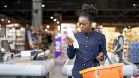 Shocked upset African American female customer looking at cashier bill fiscal receipt after shopping in grocery store supermarket. Dissatisfied shopper is surprised at high prices checking paper check - Powered by Shutterstock - Get 15% off with code: PIKWIZARD15