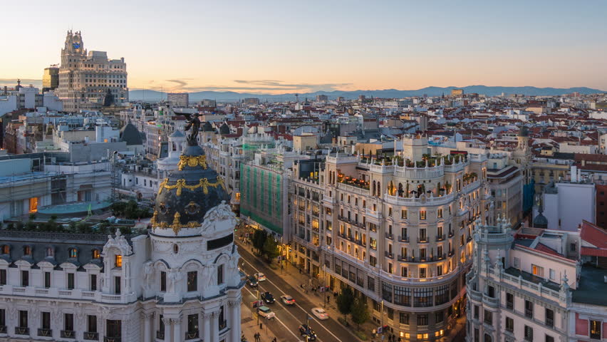 Day to night timelapse showing historic buildings and traffic on Gran Via street in Madrid, Spain, zooming out. 