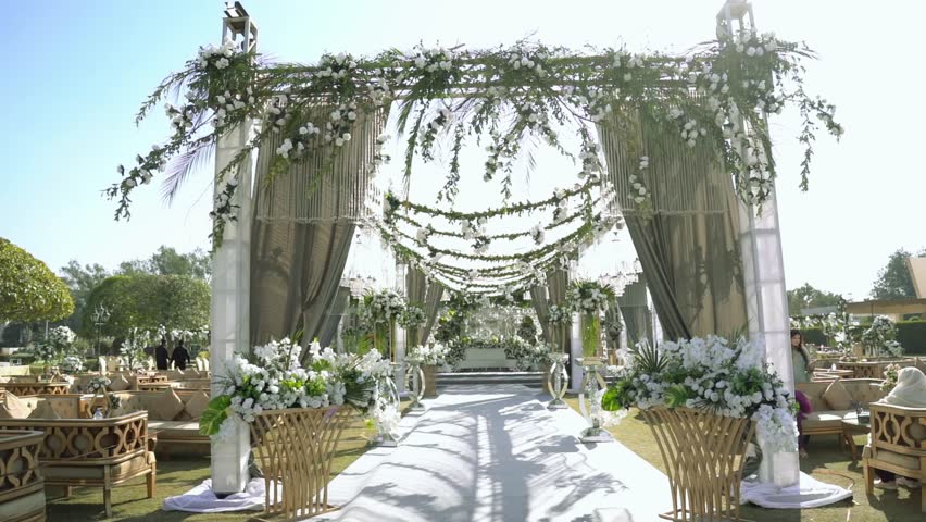 Luxurious wedding ceremony decor featuring a floral arch, petal-strewn aisle, and elegant stage. White blooms create a stunning, cinematic backdrop for the bridal entrance.