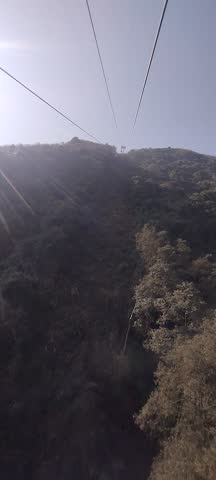 Aerial view from a cable car over a dense city in a mountain valley, likely Kathmandu, Nepal. Scenic travel and urban landscape perspective.



