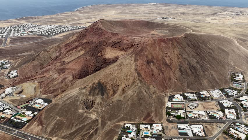 Aerial view circling Montana Roja volcanic mountain establishing the Lanzarote island coastline