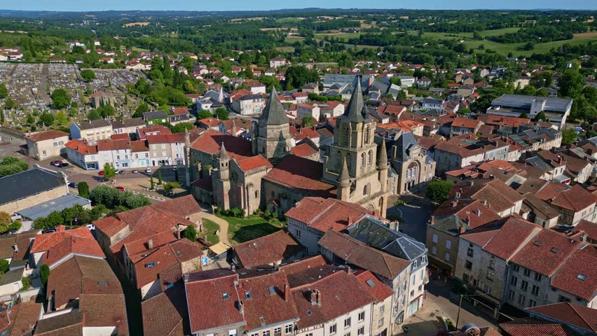 Collegiate Church of Saint-Junien and surrounding town on a sunny day, France. Aerial drone forward