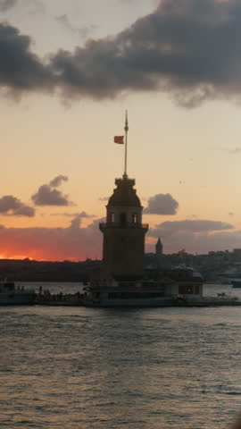 Silhouette of woman looking toward Maiden’s Tower over the sea during beautiful sunset, symbolizing reflection, hope, and cultural heritage. vertical video
