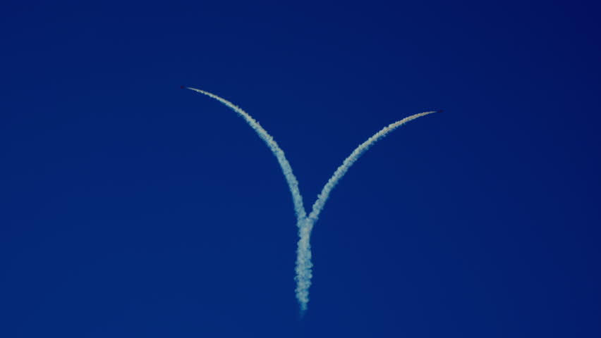 Three jet planes perform synchronized aerobatic stunt leaving heart-shaped smoke trail in clear blue sky