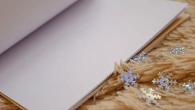 Blank notepad, turning empty pages, place for text. New year's goals notebook. Christmas decorations and warm beige plaid. Empty space for text. New year celebration. - Powered by Shutterstock - Get 15% off with code: PIKWIZARD15