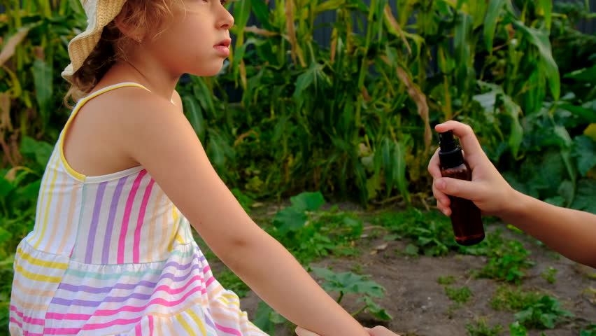 Child spraying mosquito repellent. Selective focus.