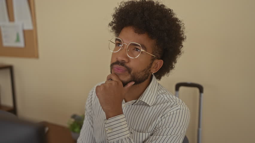 Man in an office with an idea, wearing glasses and a striped shirt, gesturing excitement in a professional indoor setting, conveying creativity and innovation.