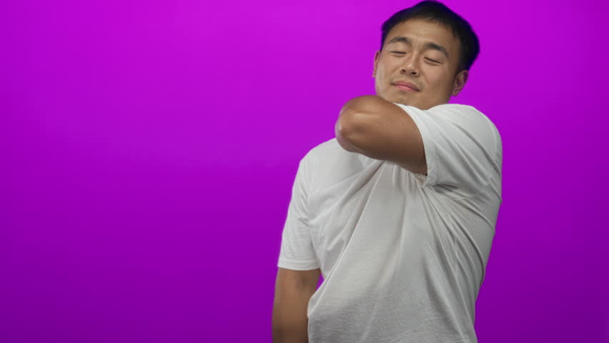 Man wearing white shirt clasping hands with bowed head and closed eyes in purple studio setting; serenity.