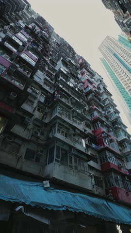 Famous Monster building with balconies and dirty blue market canopy in Hong Kong. Overpopulated apartment complex for poor people in Asian megapolis block vertical shot