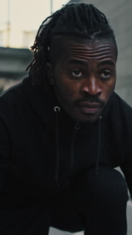 Marathon competition. Zoom out portrait of focused african american guy standing in start position and run in urban area, slow motion