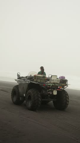 A solitary figure on a rugged all-terrain vehicle explores the desolate landscape shrouded in fog, capturing a moment of adventure and tranquility in nature.