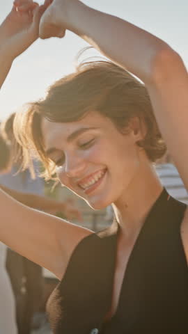 Portrait of marvelous caucasian woman making rhythmic movements with hands in front of camera and happily smiling. Young people wearing fancy attires enjoying party outside in company of best friends.