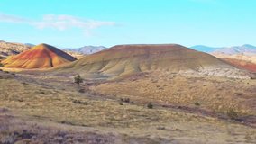 Panoramic view of the Painted Hills, showcasing their vibrant layers of red, gold, and black as seen from the elevated Carroll Rim Trail viewpoint at the John Day Fossil Beds National Monument - Powered by Shutterstock - Get 15% off with code: PIKWIZARD15
