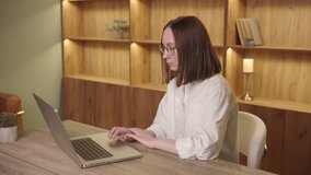 A woman with glasses looks shocked while looking at a laptop. She is sitting at a desk in a home office. - Powered by Shutterstock - Get 15% off with code: PIKWIZARD15