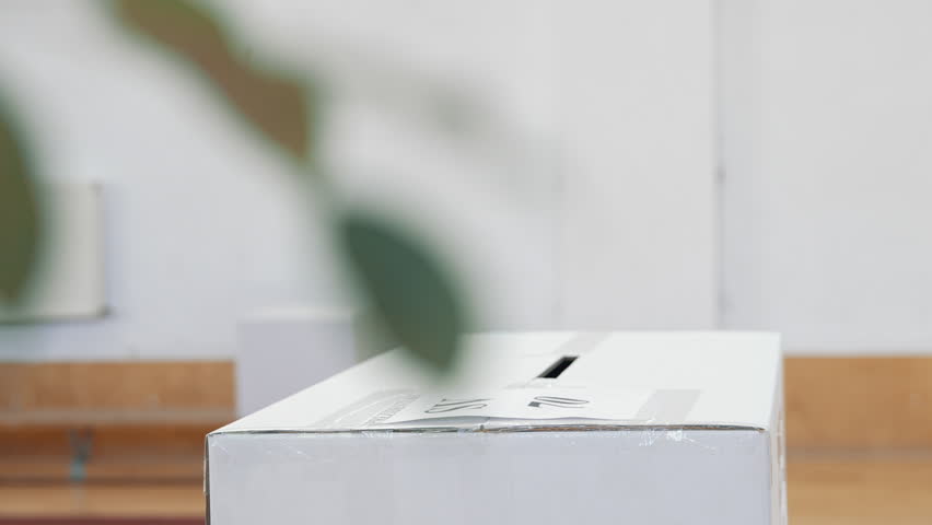 Voting box detail inside a polling station. People voting during elections