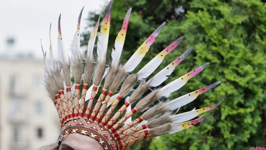Indigenous person wearing traditional feathered headdress during Latin American festival