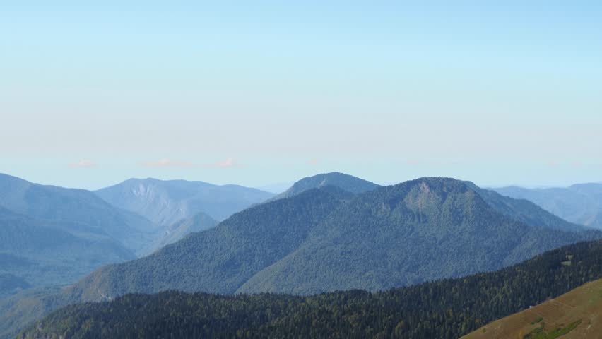 Walking in the mountains, hiking. A young woman with a backpack walks forward against the background of mountains